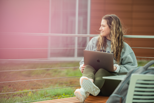 Student sitting outside on laptop looking off to the side